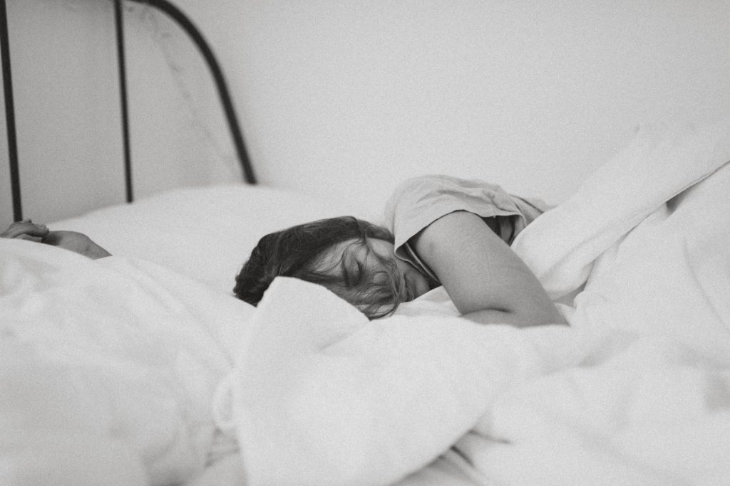 Woman sleeping in a bed with a white comforter and pillow