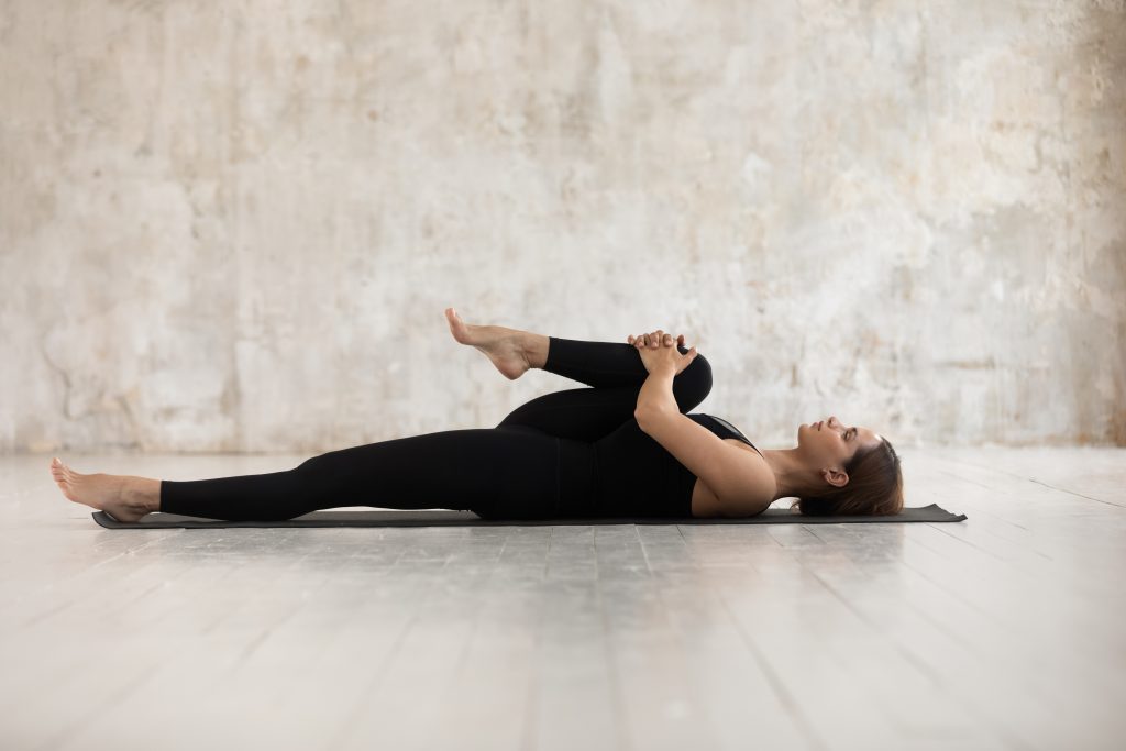woman stretching by pulling knee to chest