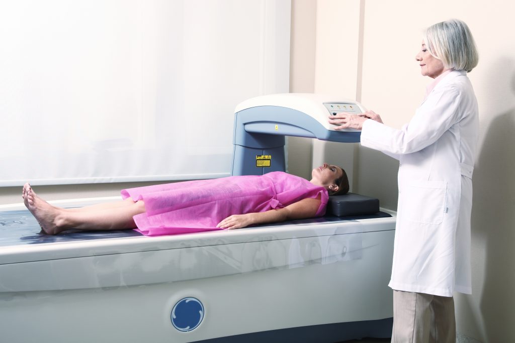 Woman receiving DEXA scan with a provider nearby