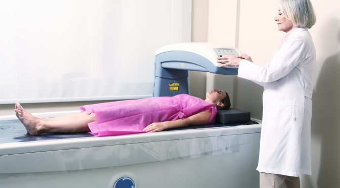 Woman receiving DEXA scan with a provider nearby