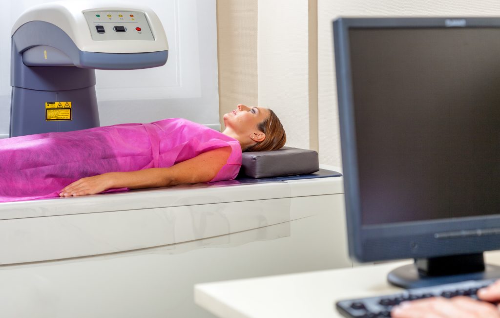 Woman in pink gown receiving DEXA scan