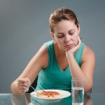 woman looking at spaghetti but doesn't want to eat it