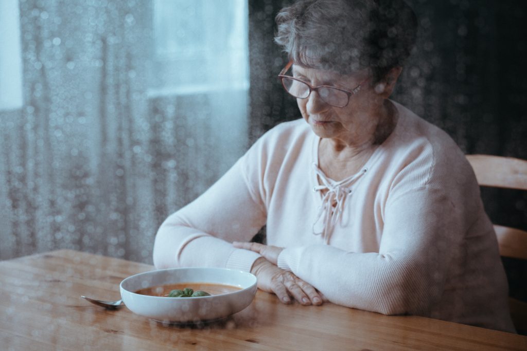 old woman looking at food sadly