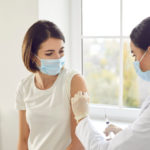 Woman about to receive a shot from a healthcare professional.