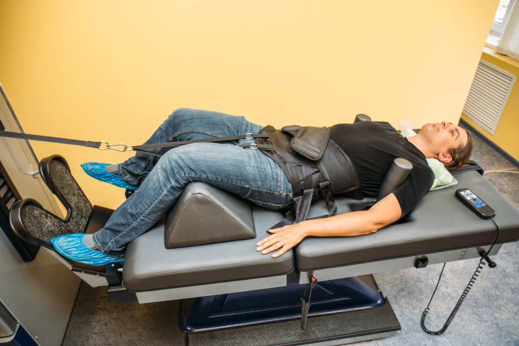 Man receiving spinal decompression treatment from a machine